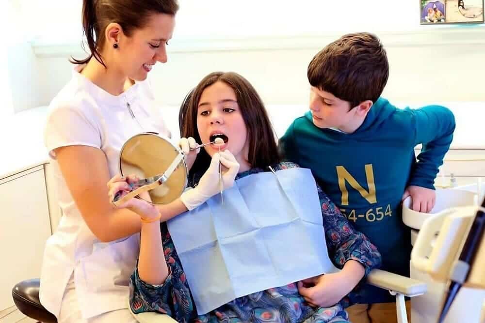 dentista ajustando aparato a chica joven