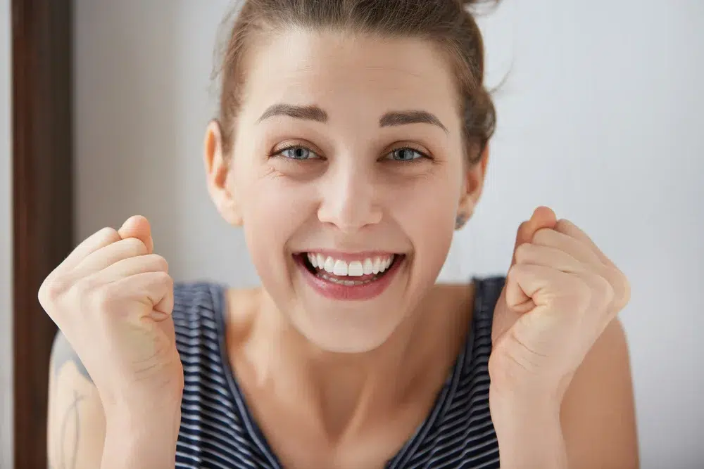 mujer ojos azules sonriendo con la boca abierta mostrando dientes